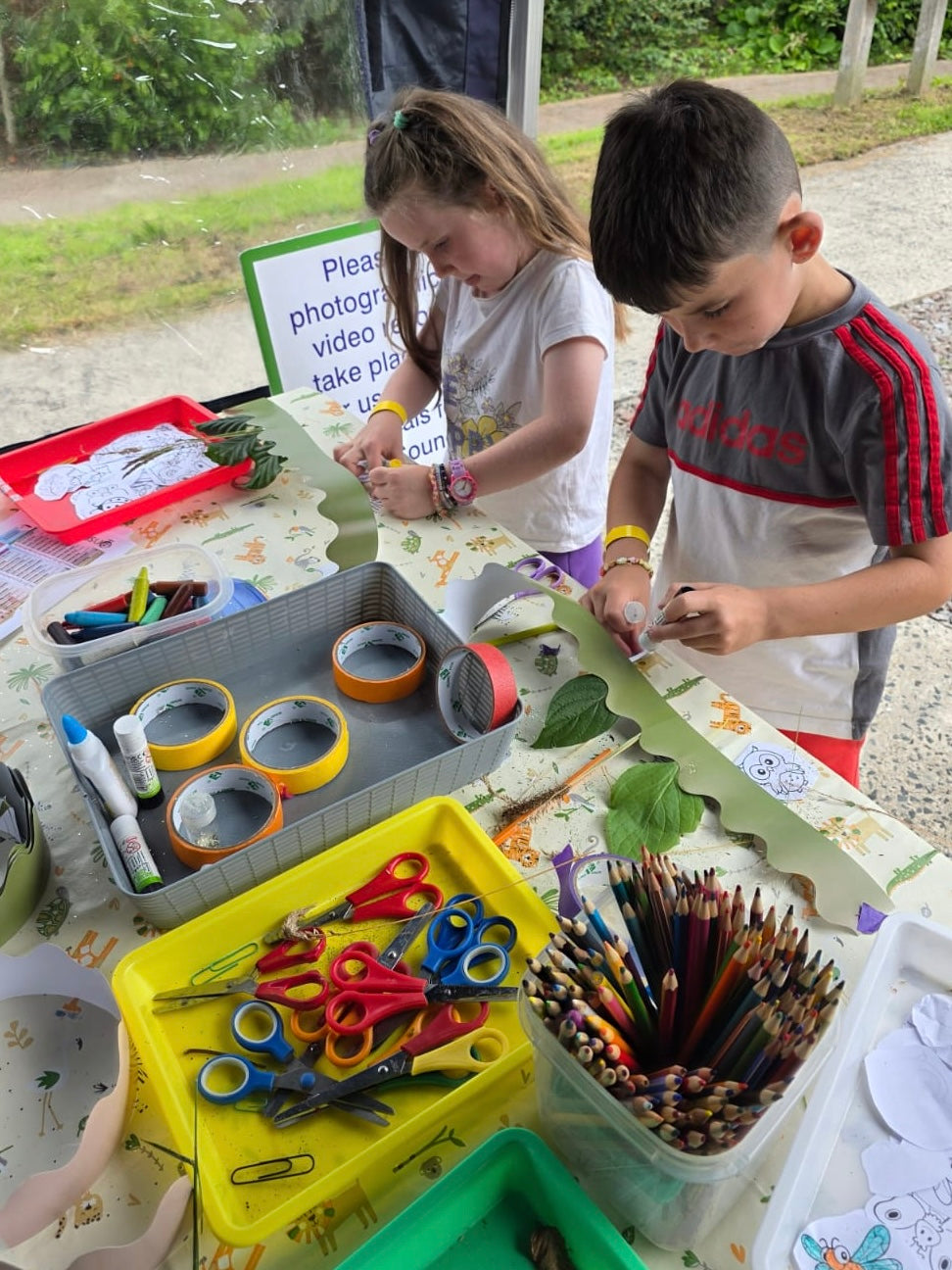 Children at a craft table with art supplies outdoors